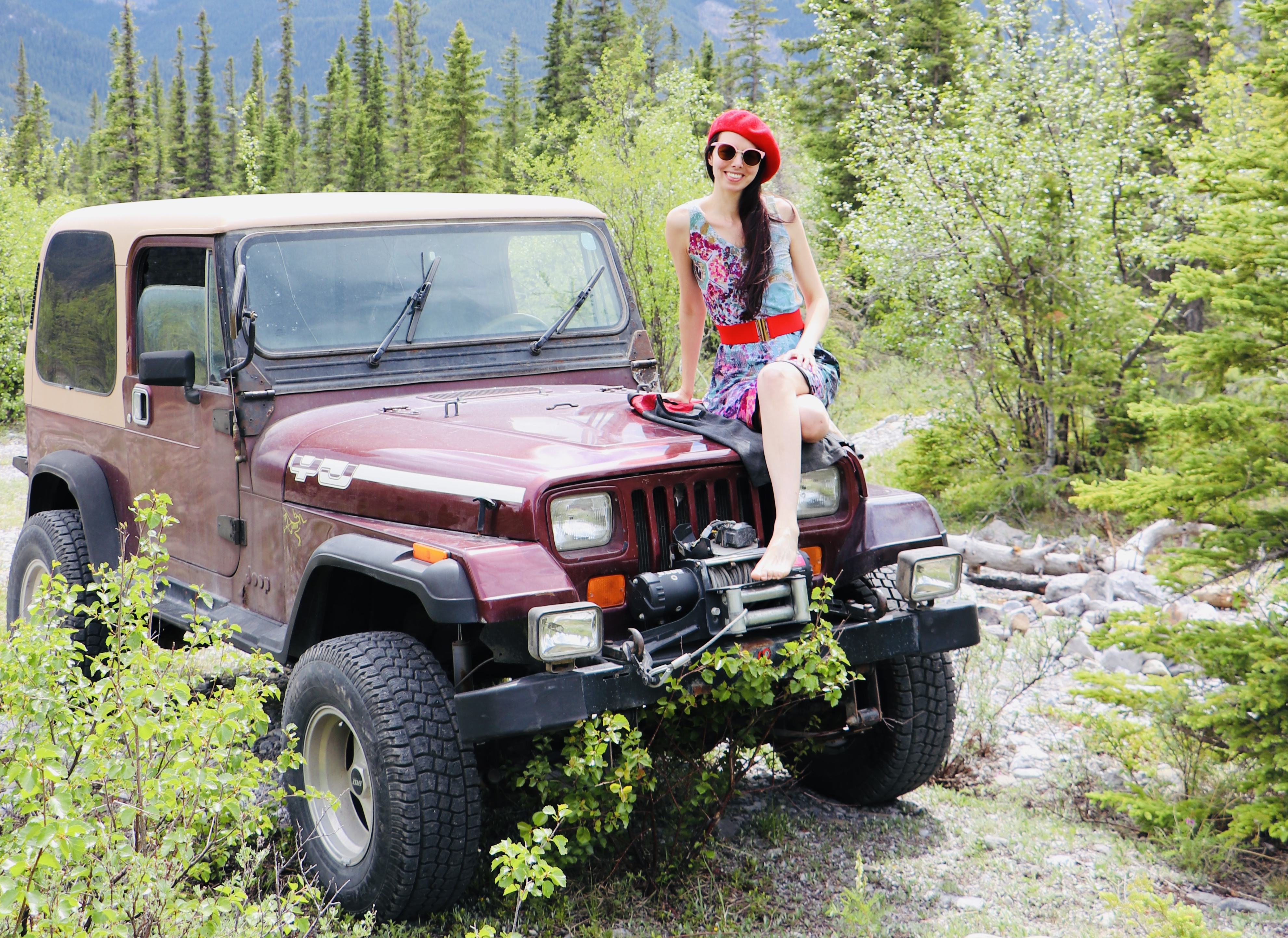 Layla Messner sitting on a vintage yj Jeep, wearing a dress printed with her colorful art. Photo by Kelly's Perspective