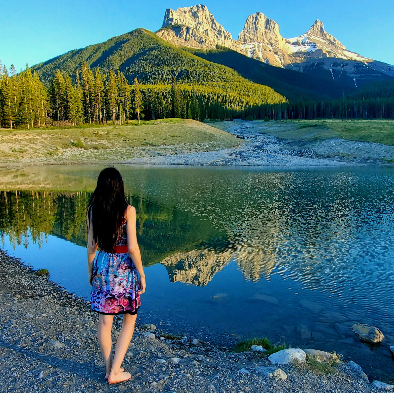 Artist Layla Messner in nature wearing a dress custom-printed with her art, the Three Sisters Mountains in the background. Photo by Kelly's Perspective.