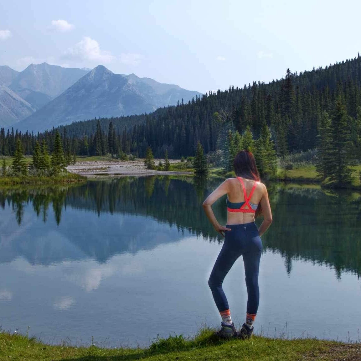 Layla Messner, the Instinctual Woman, beside a lake in a sports bra and leggings. Photo by Kelly's perspective.