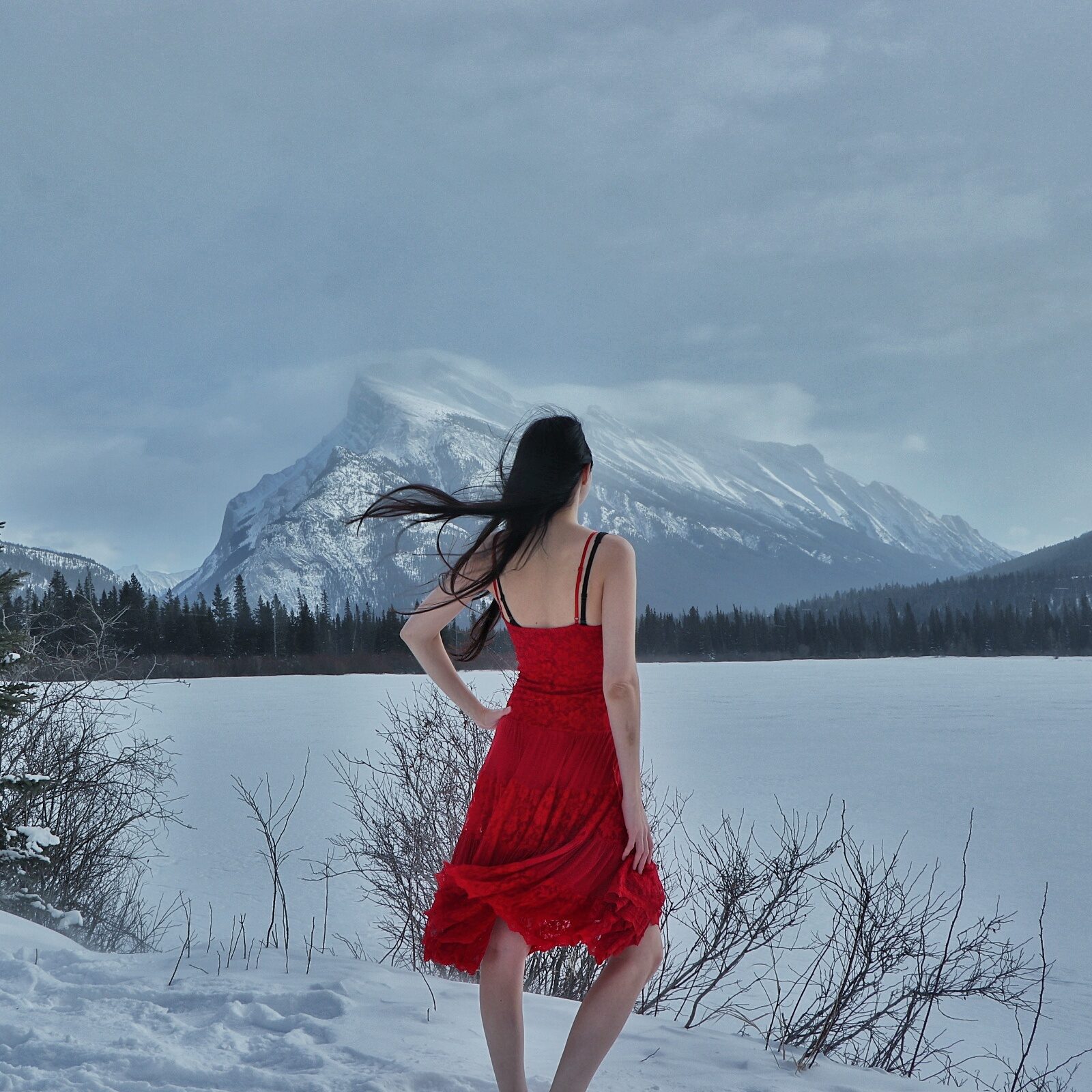 Layla Messner, The Instinctual Woman, in a red lace corset dress in the snow at Vermillion Lakes in Banff National Park