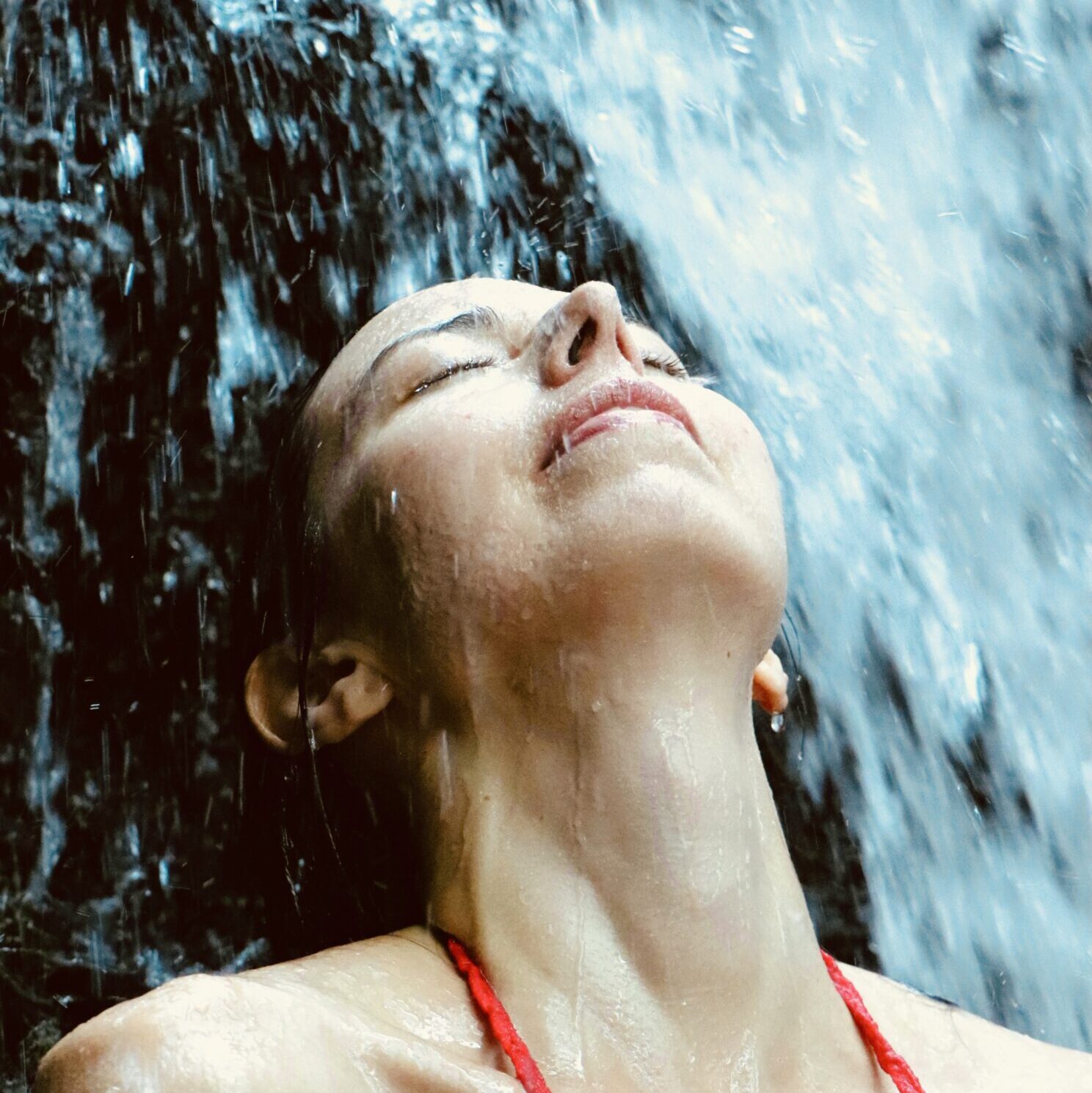 Layla Messner, The Instinctual Woman, in a waterfall, wearing a red halter top. Portrait by Kelly Russell.